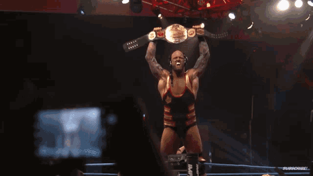 a wrestler holding a canadian heavyweight championship belt over his head