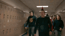 a group of young men are walking down a hallway in a school with their mouths open .