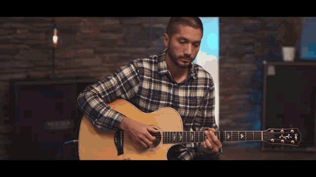 a man in a plaid shirt plays a guitar