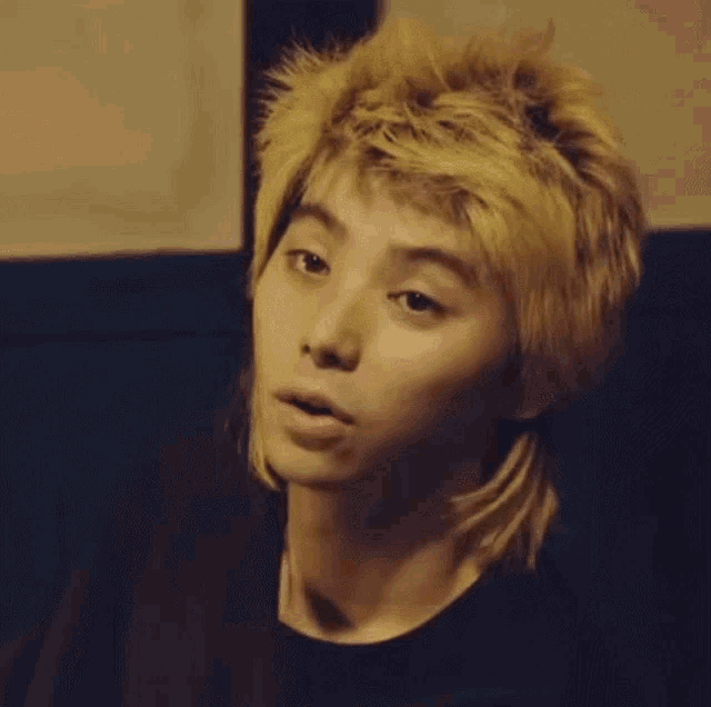 a young man with a mullet hairstyle looks at the camera
