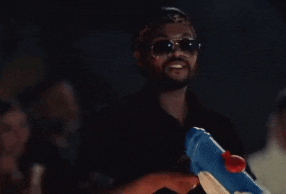 a man wearing sunglasses is holding a water gun in his hand .