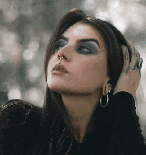 a close up of a woman 's face with a nose ring and hoop earrings