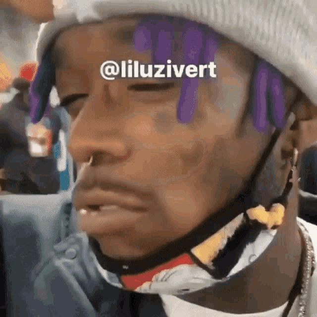 a close up of a person 's face with purple hair and a hat .