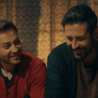 two men are sitting next to each other and one is wearing a red shirt