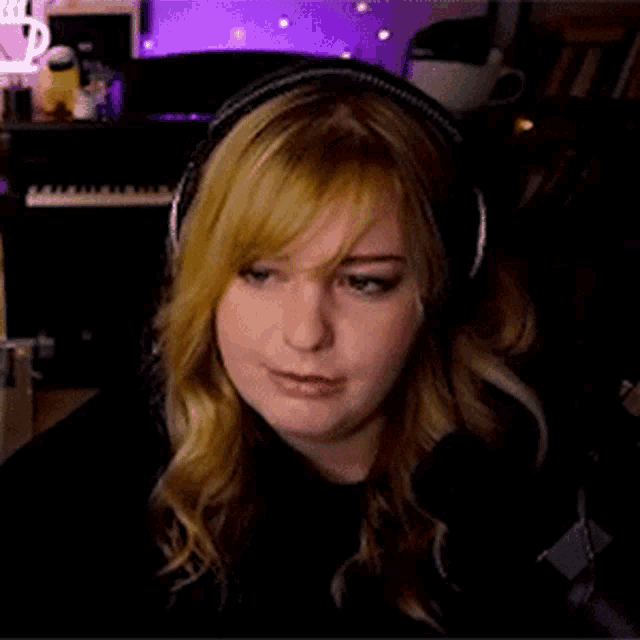 a woman wearing headphones is sitting in front of a microphone and a keyboard .