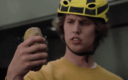 a man wearing a helmet holds a potato in his hand