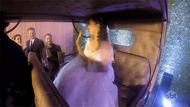 a bride in a wedding dress is sitting in a car with a sbt logo