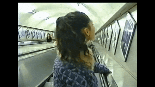 a woman is walking down an escalator in a subway station