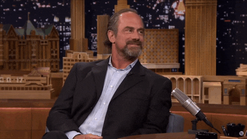 a man in a suit is sitting in front of a microphone with the time of 8:17