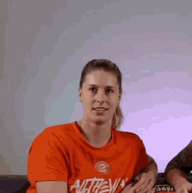 a woman wearing an orange t-shirt that says alltheway