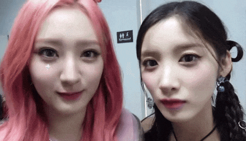 two girls with pink hair are standing next to each other in front of a sign that says restroom