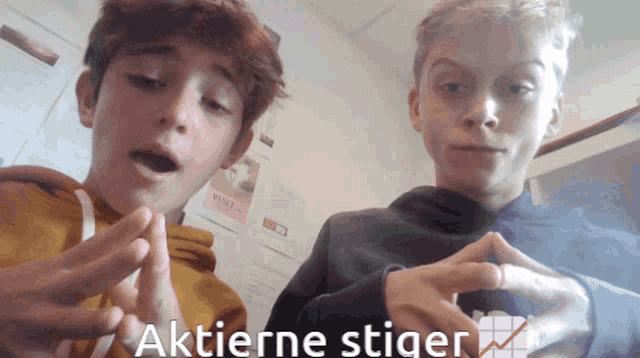 two boys are playing with their hands and the words aktierne stiger are visible