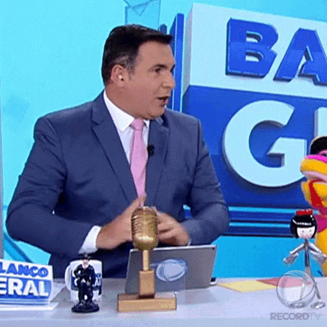 a man in a suit and tie is sitting at a desk with a sign that says banco general