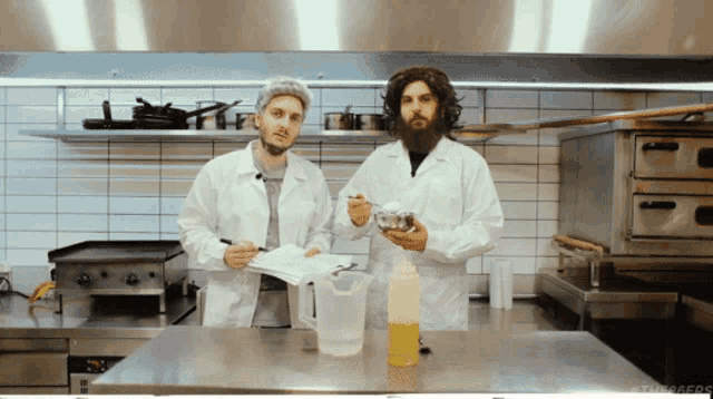 two men in white coats are standing in a kitchen with a bottle of liquid in front of them