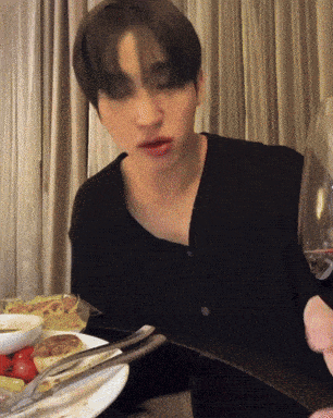 a man sitting at a table with a plate of food and a glass of wine