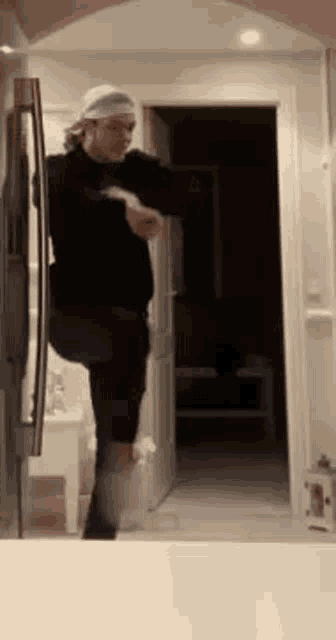 a man is standing on one leg in front of a refrigerator door .