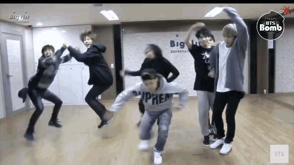 a group of young men are jumping in the air in front of a sign that says big hit