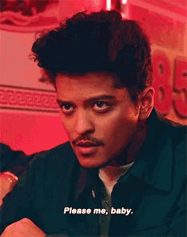 a man with a mustache says please me baby in a red room