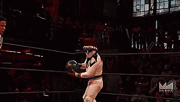 a wrestler is holding a ball in a ring with the letters m and mtv visible in the background