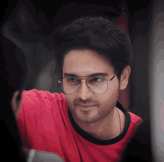 a man wearing glasses and a red shirt is smiling