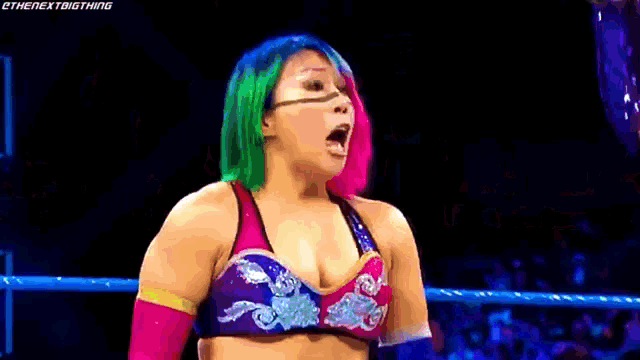 a woman with green hair is standing in a wrestling ring with her mouth open