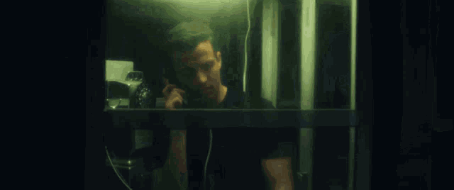 a man in sunglasses is talking on a phone in a pay phone booth