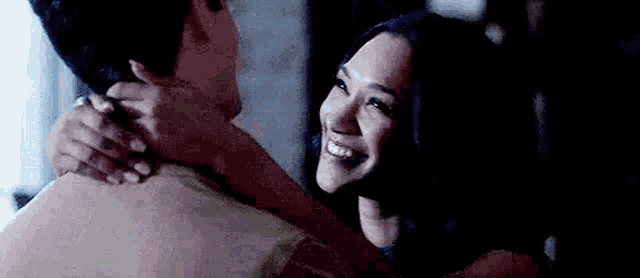 a man and a woman are hugging each other and smiling at each other .