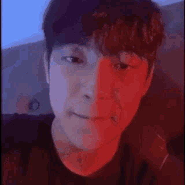 a close up of a man 's face with a red and blue background