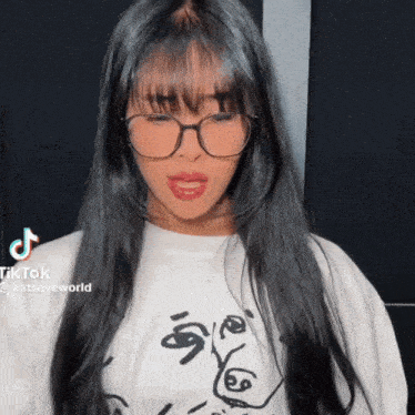 a woman wearing glasses and a white shirt with a drawing on it