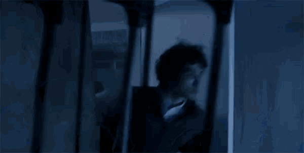 a man in a dark room is holding a knife in his hand .