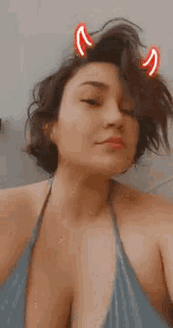 a woman with devil horns on her head is wearing a bikini top .