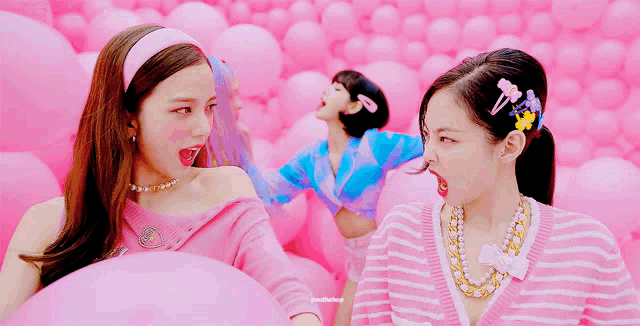 a girl in a pink and blue striped sweater is talking to another girl in a pink background
