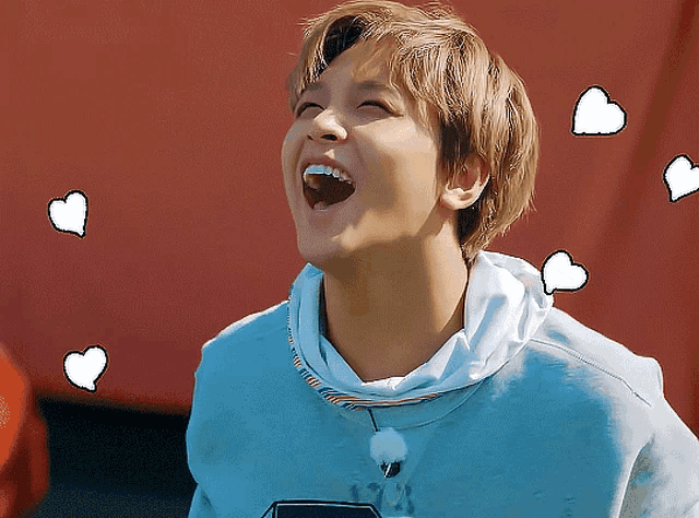 a young man in a blue sweatshirt is laughing with hearts around him