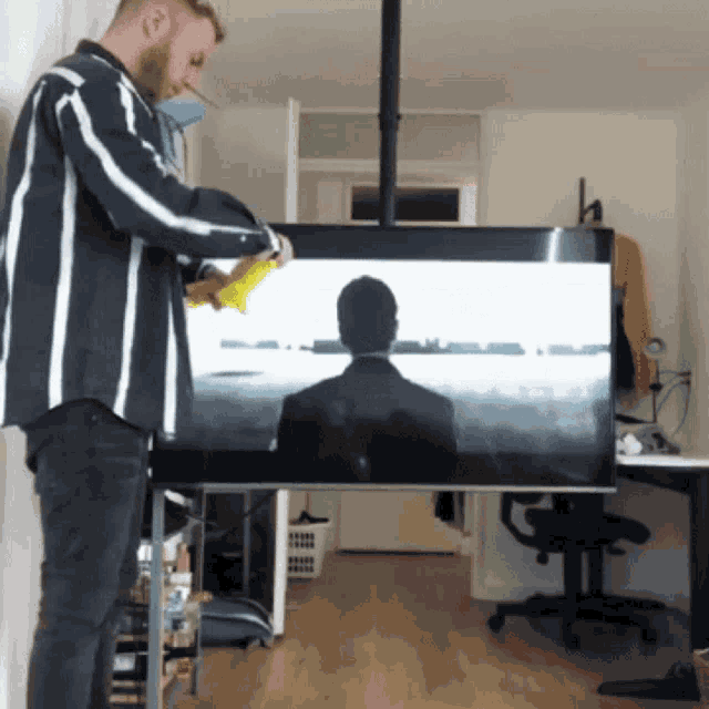 a man is cleaning a large flat screen tv
