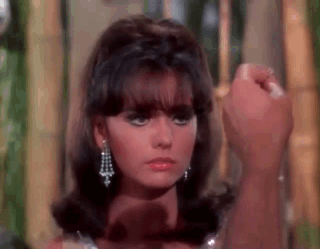 a close up of a woman 's face with a man 's hand holding her hair .