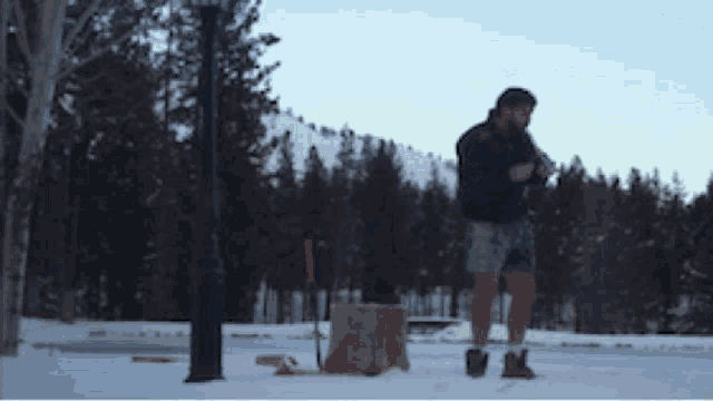 a man in shorts is standing in the snow holding a can of soda