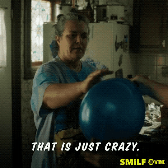a woman in a blue shirt is holding a blue balloon and says that is just crazy