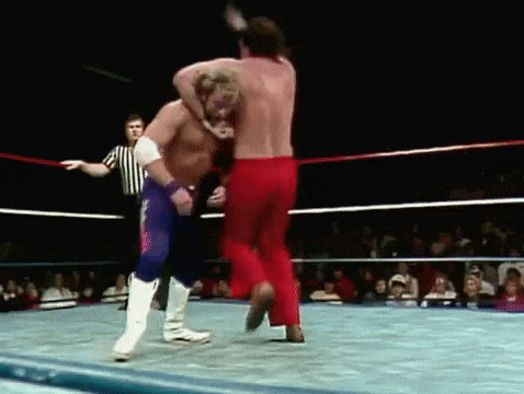 two wrestlers are fighting in a ring with a referee watching
