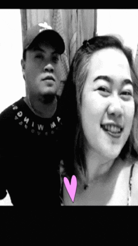 a man and a woman are posing for a picture with a pink heart in the middle