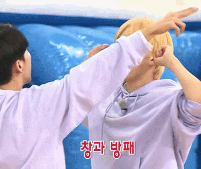 a man in a purple shirt is pointing at another man