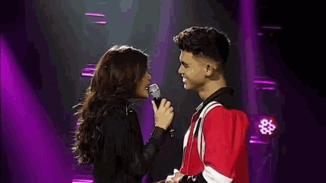 a man and a woman singing into microphones on a stage .