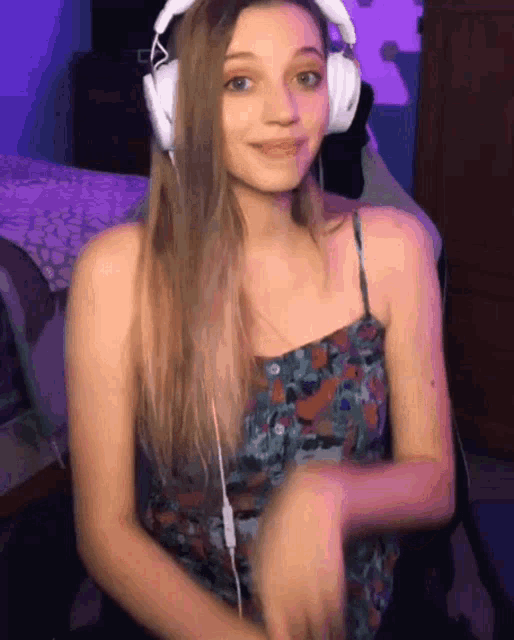 a girl wearing headphones and a floral dress is smiling