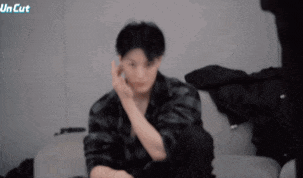 a man is sitting on a couch with his hands on his ears .