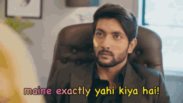 a man in a suit is sitting in a chair with the words maine exactly yahi kiya hai written above him
