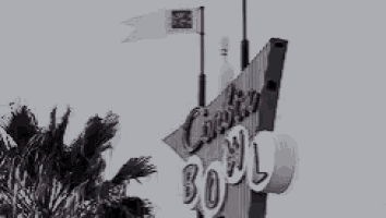 a black and white photo of a bowling alley sign with a flag flying in the background .