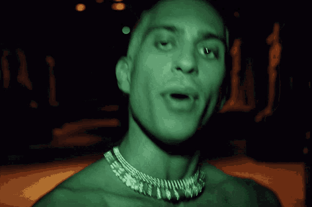 a close up of a man 's face with a necklace on