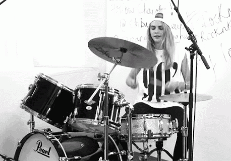 a girl is playing drums in front of a white board .