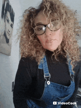a woman with curly hair wearing overalls and glasses has a video cook watermark