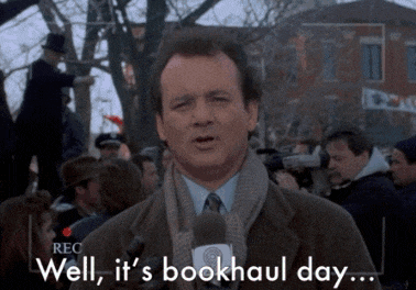 a man talking into a microphone with the words well it 's bookhaul day behind him
