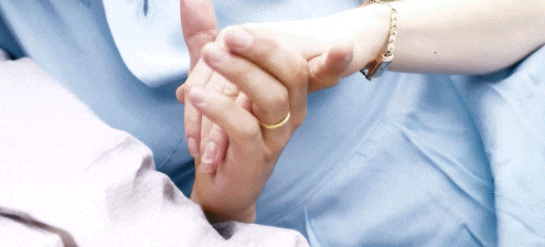 a person holding another person 's hand with a gold ring on their finger